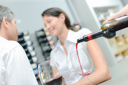 Waiter pouring wine for a couple