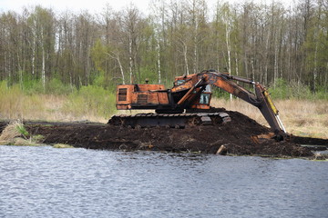 old abandoned excavator on peat bogs in the middle of the water