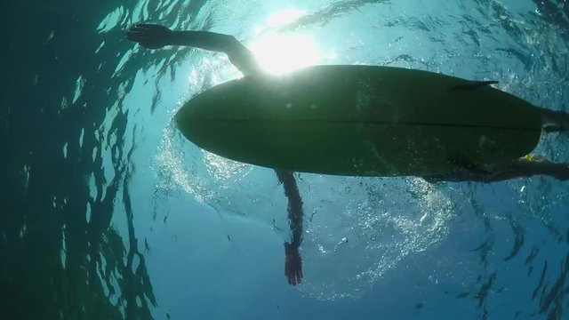 SLOW MOTION UNDERWATER: Surfer sportsman paddling on a surf in open water ocean