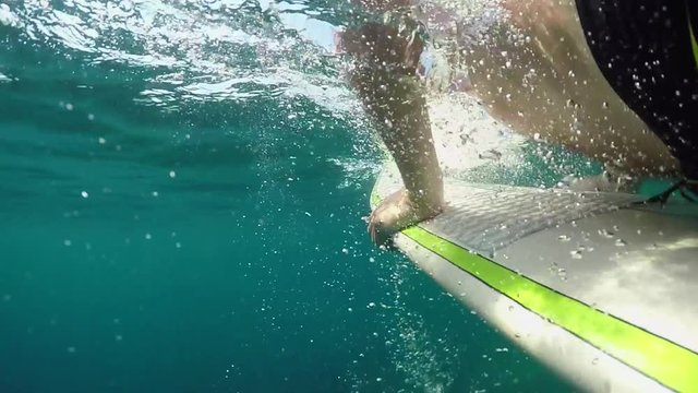SLOW MOTION, UNDERWATER: Unrecognizable surfer paddling out catching reef break