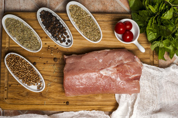 Fresh meat selection on wooden cutting board with spices in a white bowl