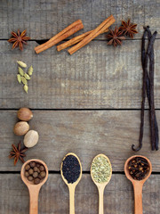 composition of spices on wooden background: allspice, cloves, fennel, star anise, vanilla, cinnamon, green cardamom, nutmeg, black sesame. View from above. copy space