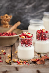Fresh yogurt with pomegranate seeds and walnut in a glass jars