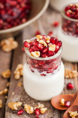 Fresh yogurt with pomegranate seeds and walnut in a glass jars