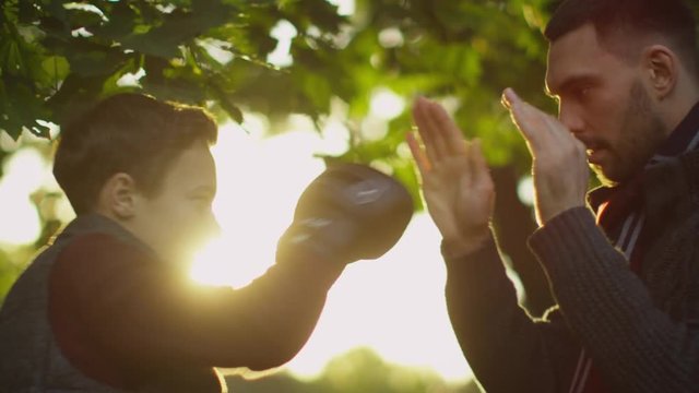 Father Teaches his Son Boxing with Gloves. Recreactional Activities in the Autumnt Park. Shot on RED Cinema Camera in 4K (UHD) 