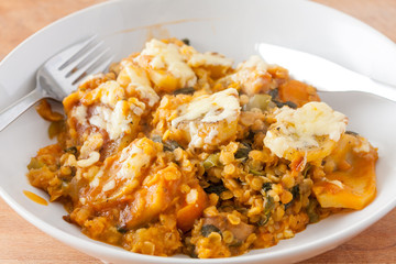 Lentil and vegetable hotpot with a cheesy potato topping in a white china bowl