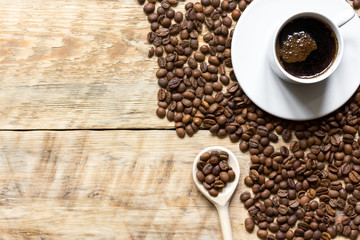 cup of coffee, beans and spoon on wooden background