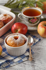 Baked apples on white plate with cup of tea