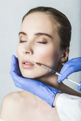 Doctor aesthetician makes lips correction and augmentation to female patient