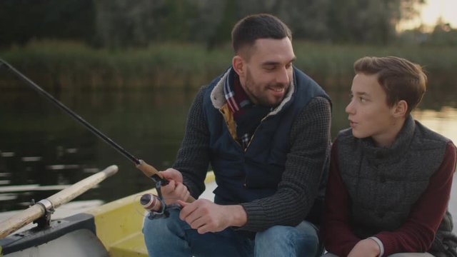Father and Son Sitting in the Boat Fishing. Father Swings Fishing Rod. Shot on RED Cinema Camera in 4K (UHD) 