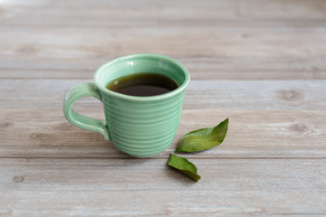 cup or mug of black tea with green leaves