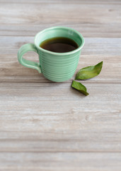 cup or mug of black tea with green leaves