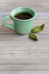 cup or mug of black tea with green leaves