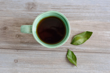 cup or mug of black tea with green leaves