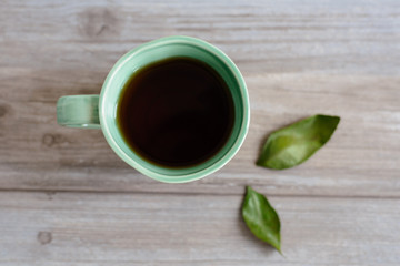 cup or mug of black tea with green leaves