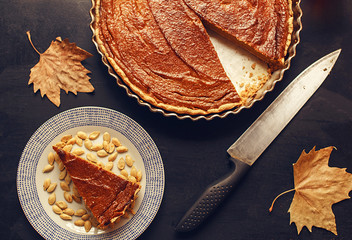 Pumpkin pie with a slice and autumn leafs. Thanksgiving.