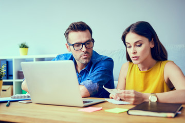 Worried couple paying bills online at home with laptop