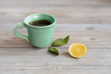 cup or mug of black tea with green leaves and lemon