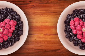 Ceramic plates with heart shaped berries on the sides of the wooden table with clipping path. Top view.
