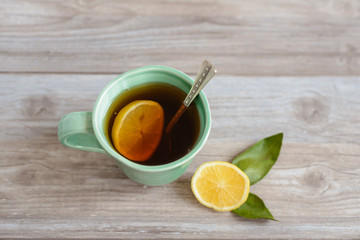 cup or mug of black tea with green leaves and lemon