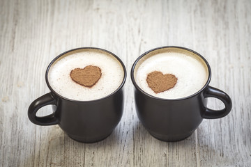Two coffee cups with cinnamon heart shape