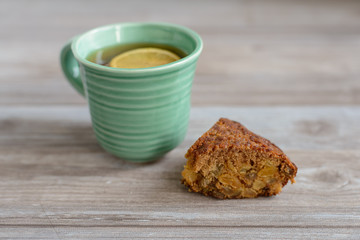 cup or mug of black tea with lemon slice and piece of cake