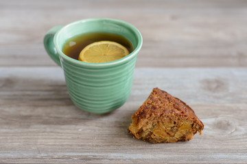 cup or mug of black tea with lemon slice and piece of cake