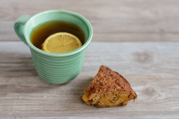 cup or mug of black tea with lemon slice and piece of cake