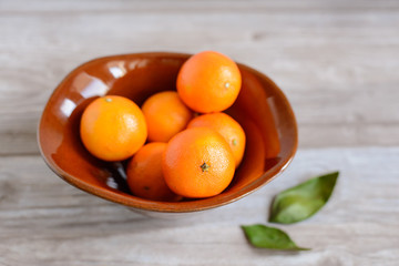 brown ceramic vase with oranges on wooden table