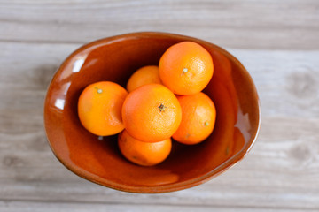 brown ceramic vase with oranges on wooden table
