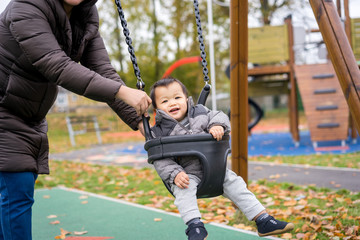 Obraz premium Baby and mother paly swing in the park