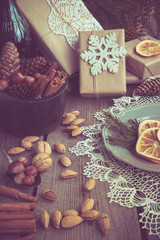 Christmas still life with delicious, almond, cinnamon, snowflakes on wooden table. Top view. Toned image. Vintage effect.