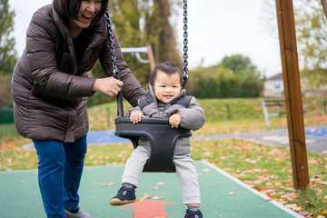 Obraz premium Baby and mother paly swing in the park