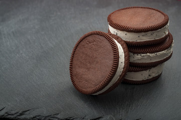 Round vanilla and cookie ice cream sandwich bar leaning against a stack of three ice cream sandwiches with copy space - Powered by Adobe
