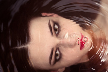 beautiful woman soaks in the warm water and looking at camera, closeup portrait