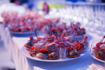 Catering banquet table with baked food snacks, sandwiches, cakes, cups and plates, self serve, open...