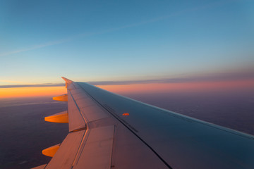 Fototapeta na wymiar Airplane's window shot during the sunrise and cloudy sky