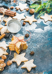 Gingerbread Christmas star shaped cookies with cinnamon, anise and nuts served with fir-tree branch on dark plywood background, selective focus, copy space, vertical composition