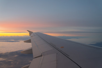 Fototapeta na wymiar Airplane's window shot during the sunrise and cloudy sky