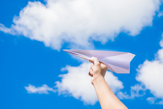 plane paper in children hand and blue sky in cloudy day.