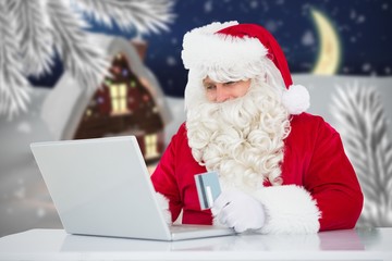 Santa claus doing online shopping with credit card on laptop