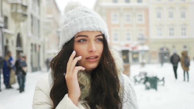 happiness, winter holidays, christmas, beverages and people concept - happy girl talking on the phone city snow winter christmas