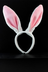 Pink and white Easter costume bunny ears on black background. Vertical.