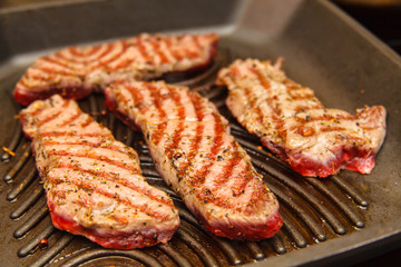 Slices of beef strip loin stir-fried in a skillet-grill, visible