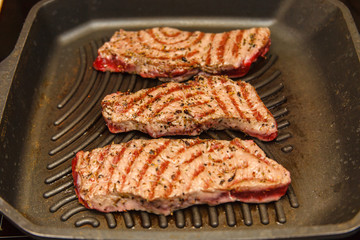 Slices of beef strip loin stir-fried in a skillet-grill, visible