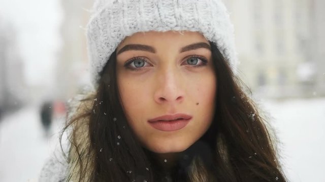 Street emotional portrait of young beautiful woman in city Model looking at camera. Lady wearing stylish classic winter knitted clothes. Christmas concept. Snowfall