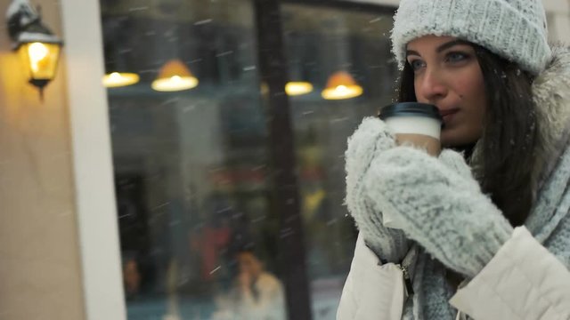 happiness, winter holidays, christmas, beverages and people concept - Pretty young brunette drinking coffee outside on winter