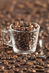 Transparent glass cup with coffee beans and a spoon