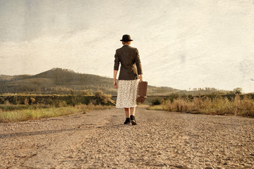 Women with vintage suitcase at old road. Photo in retro style