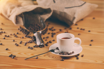 Cup of coffee, bag and scoop on old wooden background